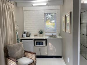 a kitchen with a counter with a microwave and a chair at The Stables on Drew Avenue in Howick