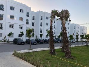 zwei Palmen auf einem Parkplatz vor einem Gebäude in der Unterkunft Superbe Appartement meuble Alliance Darna Tanger in Tangier