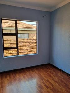 een lege kamer met een groot raam en houten vloeren bij Sunny Estate in Katlehong