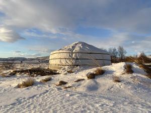 a yurt in a snowy field with a mound of snow at Náttúra Yurtel in Haukadalur
