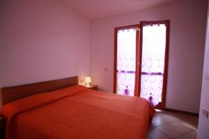 um quarto com uma cama vermelha e uma janela em Beautiful villa with private garden and porch em Rosolina Mare