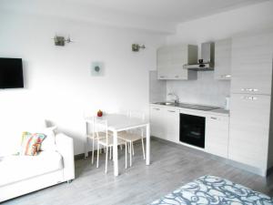a white kitchen with a table and a white couch at Direttamente Al Lago Apartments in Marone