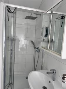 een badkamer met een douche, een wastafel en een spiegel bij Prime Host apartments in Karlsruhe