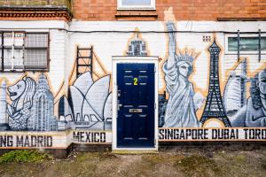 a wall with a blue door in front of a mural at Harrow Road Stay Central+Parking in Leicester