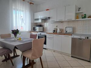 a kitchen with white cabinets and a table with chairs at Guest House Angela in Senj