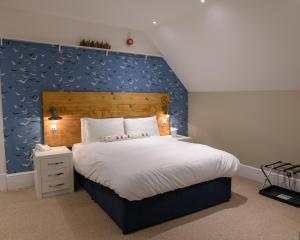 a bedroom with a large bed with a blue wall at The Randolph Hotel in Southwold