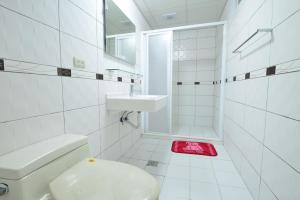 a white bathroom with a toilet and a sink at Swallow Home in Hengchun