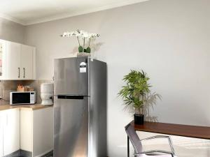 Private Unit underneath a family Home في Cherrybrook: ثلاجة من الحديد المقاوم للصدأ في مطبخ مع طاولة