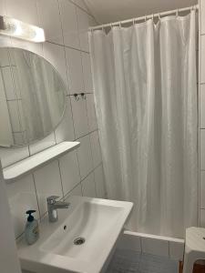 a white bathroom with a shower curtain and a sink at Appartement Imbachhorn in Zell am See