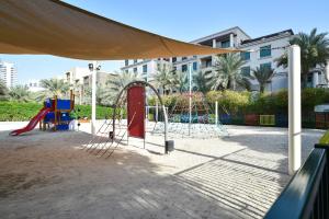 a playground with a slide and a swing set at Lovely 1 Bedroom Apartment in Greens - ADN in Dubai