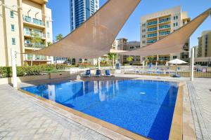 a swimming pool with umbrellas and chairs and buildings at Lovely 1 Bedroom Apartment in Greens - ADN in Dubai