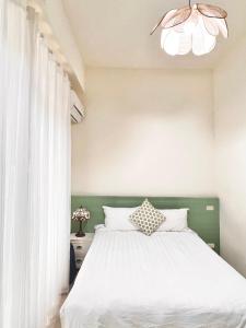 a bedroom with a bed with white sheets and a chandelier at 永安101 Wing on x 附陽台 in Taitung City