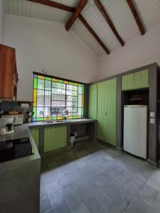 cocina con armarios verdes y nevera blanca en Casa en Camino del cuadrado Sierras de Córdoba en Río Ceballos