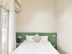 a bedroom with a white bed with a green headboard at 永安101 Wing on x 附陽台 in Taitung City