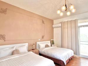 a bedroom with two beds and a window and a chandelier at 永安101 Wing on x 附陽台 in Taitung City