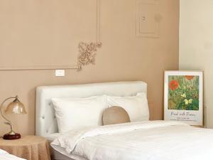 a bedroom with a white bed with a painting on the wall at 永安101 Wing on x 附陽台 in Taitung City