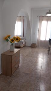a room with a dresser with a vase of sunflowers on top at Korali in Symi