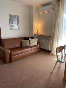 uma sala de estar com um sofá castanho e uma cadeira em Villa Baltic Apartament nr 3 em Chałupy