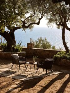 two chairs and a table on a patio under trees at Villa Anatoli - Tranquil Escape with Scenic Views, by ZanteWize in Akrotiri