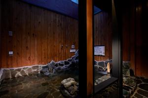 a room with a wooden wall with rocks in it at Yatomi Hotel Nuqu Natural Hot Spring 