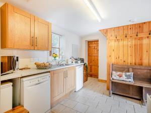 a kitchen with white appliances and wooden cabinets at Coed Y Gaer Annexe - Uk43776 in Llansilin