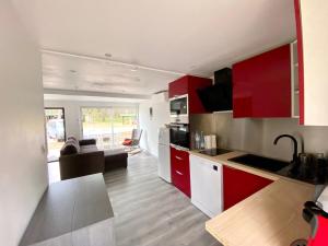 une cuisine avec des armoires rouges et un salon dans l'établissement LES COTTAGES DE LEON, à Léon