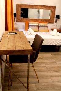 Habitación con 2 camas, mesa y escritorio. en Doble S Rooms - Hostal en Sevilla