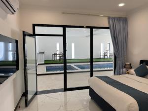 a bedroom with a bed and a television and a pool at Bedyiah Green Homes in Al Qābil