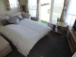 een slaapkamer met een bed en een tafel en ramen bij The Cockle Shell Caravan, Seaview Holiday Park, Whitstable in Whitstable