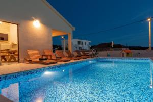 a swimming pool with chairs next to a house at Vila Vanessa Trogir - Čiovo in Trogir