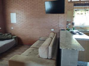a living room with a couch and a television on a brick wall at Chácara Buscapé in Mogi das Cruzes