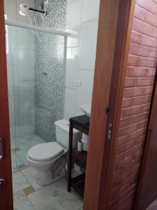uma casa de banho com um WC e uma cabina de duche em vidro. em Chácara Buscapé em Mogi das Cruzes