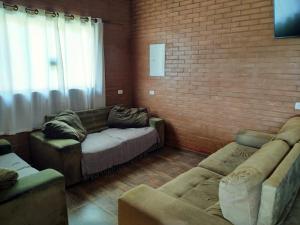 uma sala de estar com dois sofás e uma parede de tijolos em Chácara Buscapé em Mogi das Cruzes