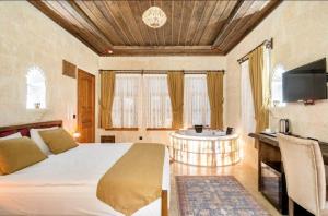 a bedroom with a bed and a sink and a tv at Uzay Cave Suite Hotel in Urgup