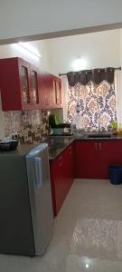 uma cozinha com armários vermelhos e um frigorífico em Beach Dreamz Villa 2 BHK Near Pondy and Auroville em Marakkānam