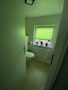 a white bathroom with a toilet and a window at Kleines Studio mit Gartenzugang in Milbitz