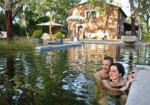 Ein Mann und eine Frau schwimmen im Wasser in der Unterkunft Valle del Arroyo Casas Rurales - B&B - Solo adultos in Cortelazor