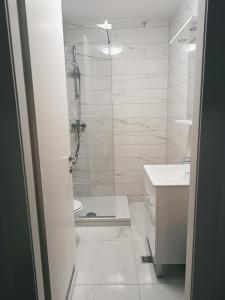 a white bathroom with a shower and a sink at Luce Gold Apartment in Zadar