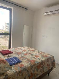 - une chambre avec un lit doté d'une couverture fleurie et d'une fenêtre dans l'établissement Excelente Ap Mobiliado (Ótima Localização) - Com Ar, à Campina Grande