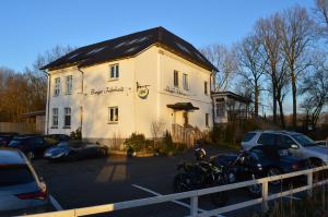 een wit gebouw met auto's geparkeerd op een parkeerplaats bij Burger Fährhaus in Burgerfeld