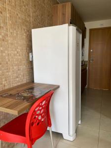 - un réfrigérateur blanc dans une cuisine avec une chaise rouge dans l'établissement Excelente Ap Mobiliado (Ótima Localização) - Com Ar, à Campina Grande