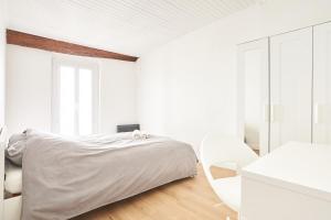 a white bedroom with a bed and a white chair at Duplex de standing en plein coeur de Béziers in Béziers