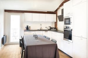 eine Küche mit weißen Schränken und einem Tisch mit Stühlen in der Unterkunft Duplex de standing en plein coeur de Béziers in Béziers