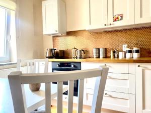 a kitchen with white cabinets and a table and chairs at Nad Młynówką in Opole
