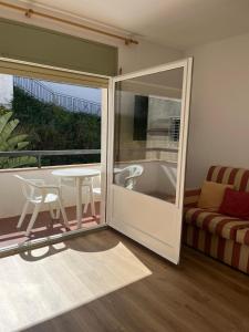 Habitación con puerta corredera de cristal, mesa y sofá. en Racó de Mar, en Palamós