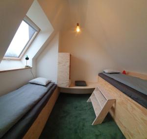 a attic room with two beds and a window at Julie's appartement aan zee - JAAZ in Nieuwpoort
