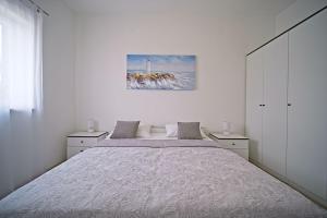 a white bedroom with a large bed and a lighthouse at Apartment Toni with spacious terrace in Postira