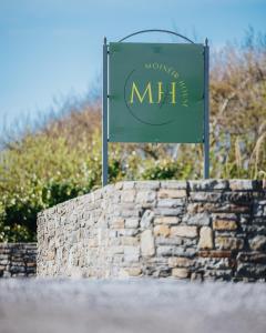 a green sign on top of a stone wall at Móinéir House in Kilkee