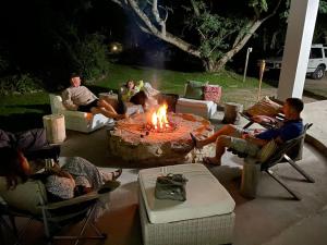 a group of people sitting around a fire pit at Farm House Plettneberg Bay in Plettenberg Bay