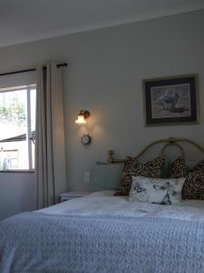 a bedroom with a bed and a window at Farm House Plettneberg Bay in Plettenberg Bay